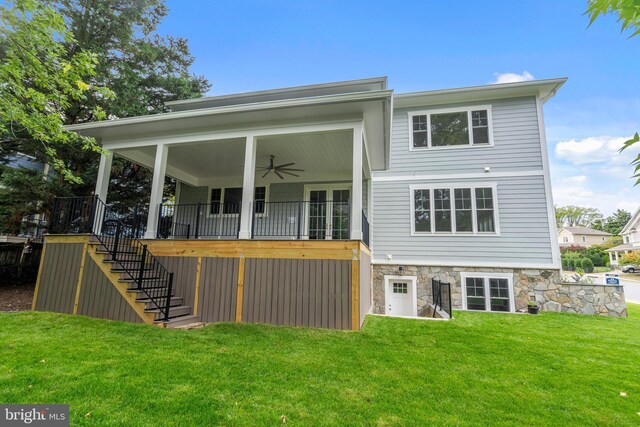 rear view of house featuring stairway, stone siding, a lawn, and a ceiling fan