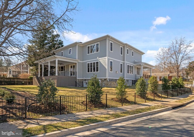 view of front facade with a ceiling fan, a porch, a front lawn, stone siding, and a fenced front yard