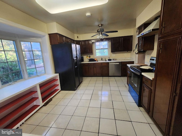 kitchen featuring wall chimney range hood, ceiling fan, light tile patterned floors, black appliances, and sink