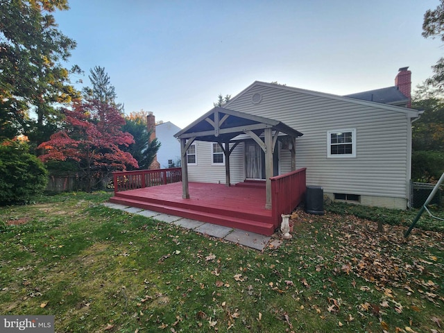 back of property with a gazebo, a deck, and a lawn