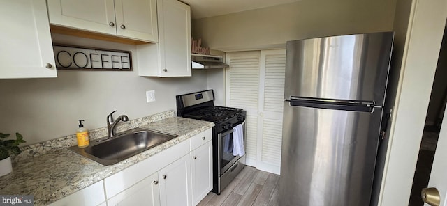 kitchen featuring sink, appliances with stainless steel finishes, light wood-type flooring, and white cabinets