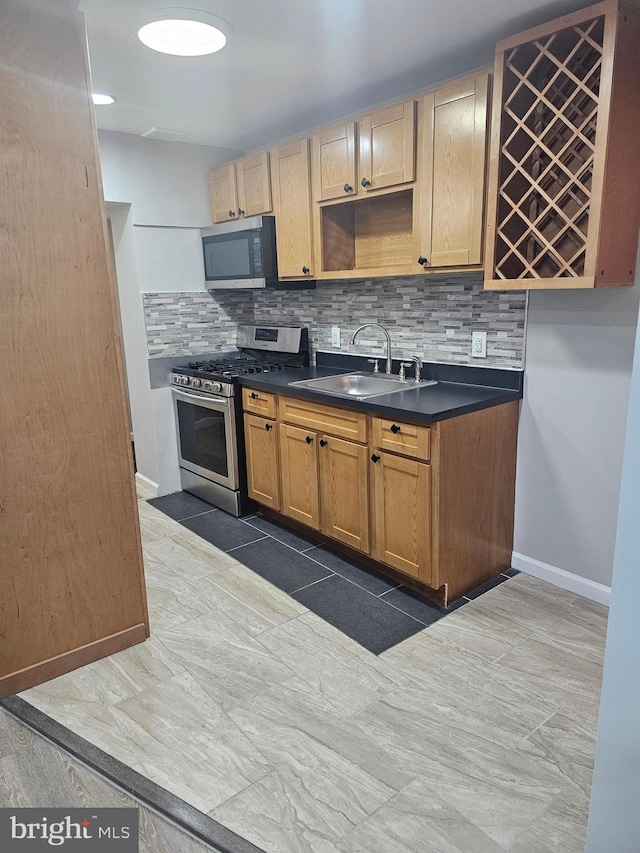 kitchen with dark tile patterned floors, stainless steel appliances, tasteful backsplash, and sink