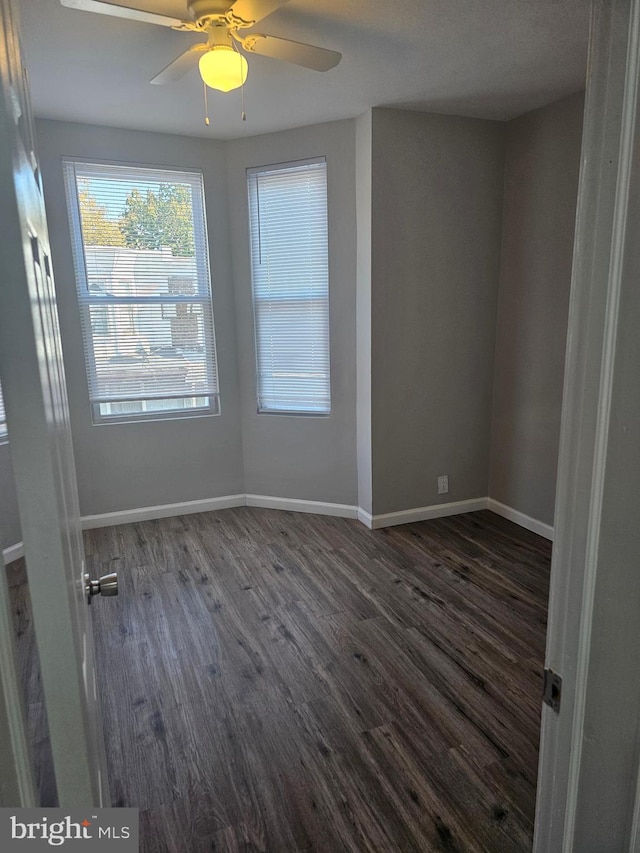 unfurnished room with ceiling fan and dark wood-type flooring