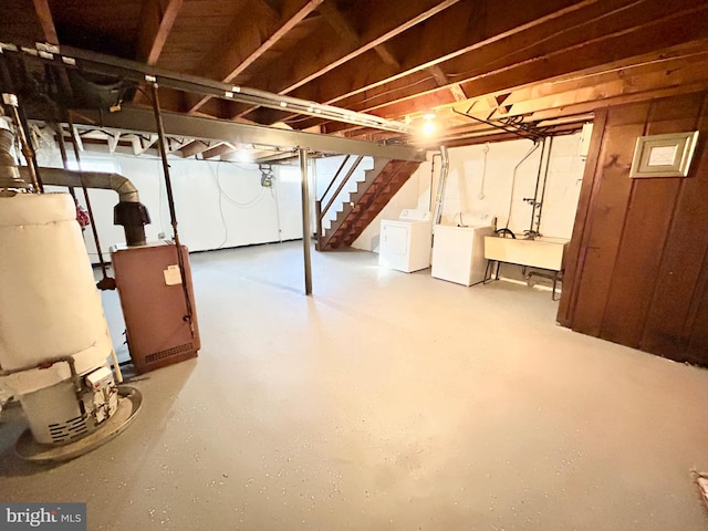 basement featuring gas water heater, sink, and independent washer and dryer