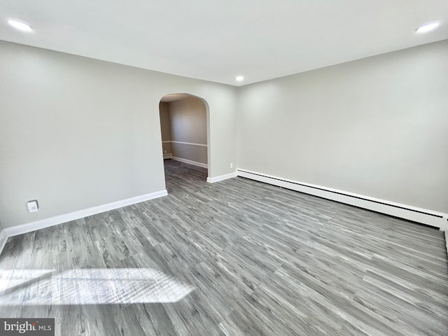 empty room with light hardwood / wood-style floors and a baseboard heating unit