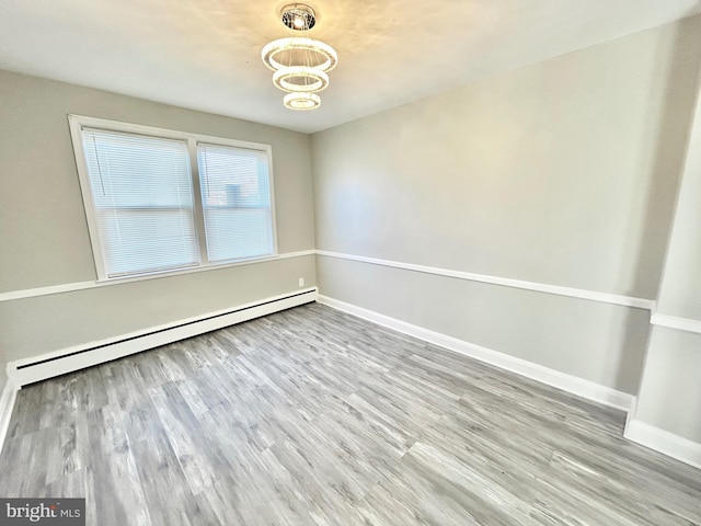 spare room with light wood-type flooring and a baseboard heating unit