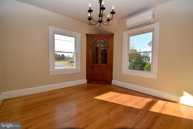 unfurnished dining area featuring light hardwood / wood-style floors, a wall mounted AC, a chandelier, and plenty of natural light