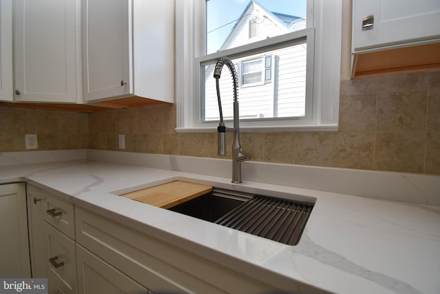 details with sink, light stone countertops, decorative backsplash, and white cabinets