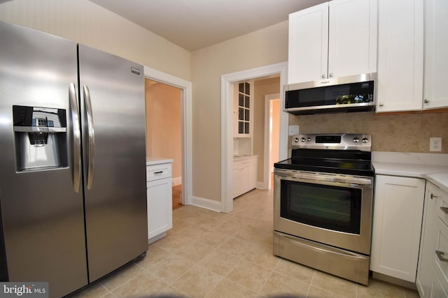 kitchen with white cabinetry, appliances with stainless steel finishes, light tile patterned floors, and decorative backsplash