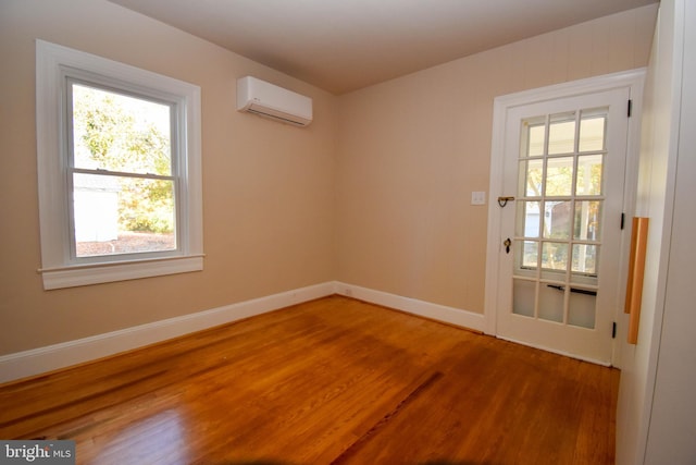 empty room featuring an AC wall unit, wood-type flooring, and a wealth of natural light