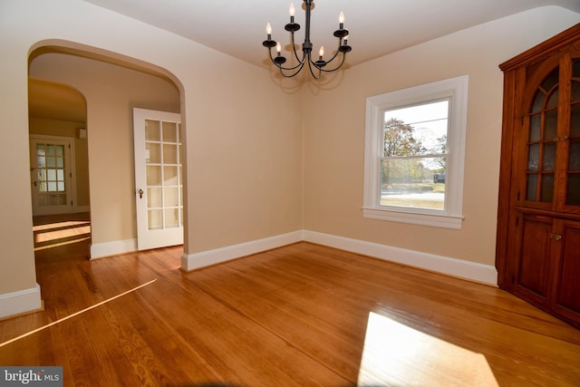 unfurnished dining area featuring a notable chandelier and hardwood / wood-style flooring