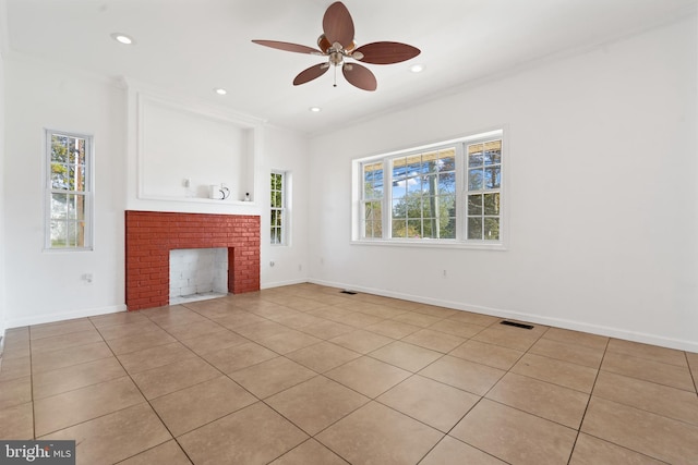 unfurnished living room with ornamental molding, ceiling fan, a brick fireplace, and plenty of natural light