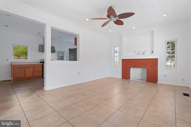 unfurnished living room with crown molding, ceiling fan, a brick fireplace, and light tile patterned floors