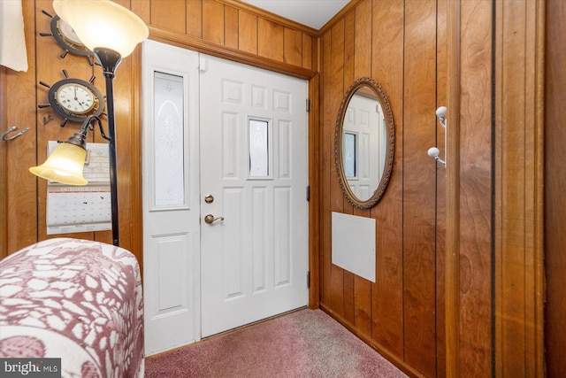 foyer with carpet flooring and wood walls