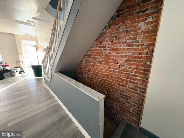 hall with hardwood / wood-style flooring and brick wall