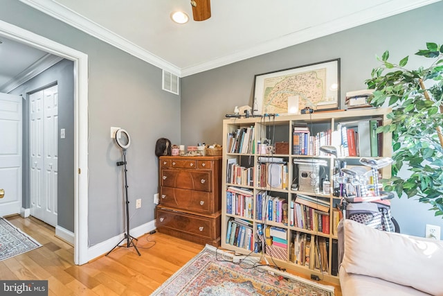 living area with hardwood / wood-style flooring and ornamental molding