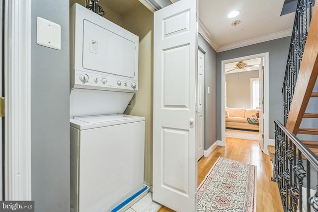 washroom featuring ornamental molding, light wood-type flooring, ceiling fan, and stacked washer / drying machine