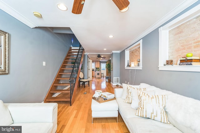 living room with crown molding, light hardwood / wood-style flooring, and ceiling fan