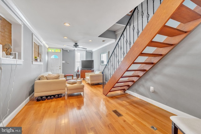 living room featuring hardwood / wood-style floors, ceiling fan, and crown molding