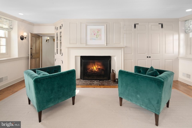 living area with light hardwood / wood-style floors and ornamental molding