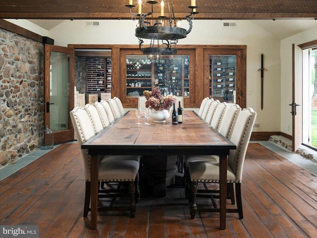 dining area with plenty of natural light, a notable chandelier, beamed ceiling, and dark hardwood / wood-style flooring