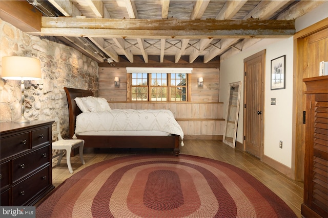 bedroom featuring hardwood / wood-style floors, beamed ceiling, and wood walls