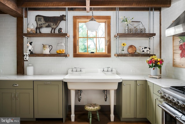 kitchen with backsplash, green cabinetry, pendant lighting, sink, and wall chimney exhaust hood