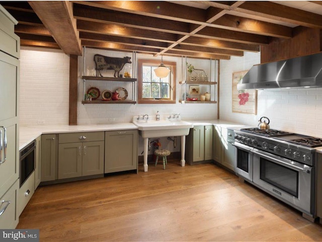 kitchen with light hardwood / wood-style floors, wall chimney exhaust hood, range with two ovens, and green cabinets