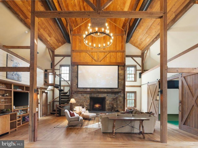 living room with a barn door, beam ceiling, light wood-type flooring, and high vaulted ceiling