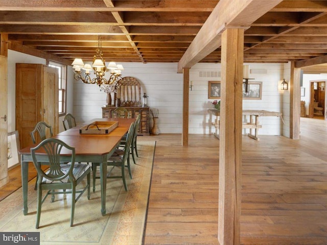 dining area featuring wooden walls, a chandelier, and hardwood / wood-style floors