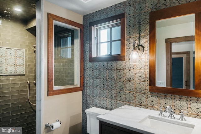 bathroom with tile walls, vanity, toilet, and a shower