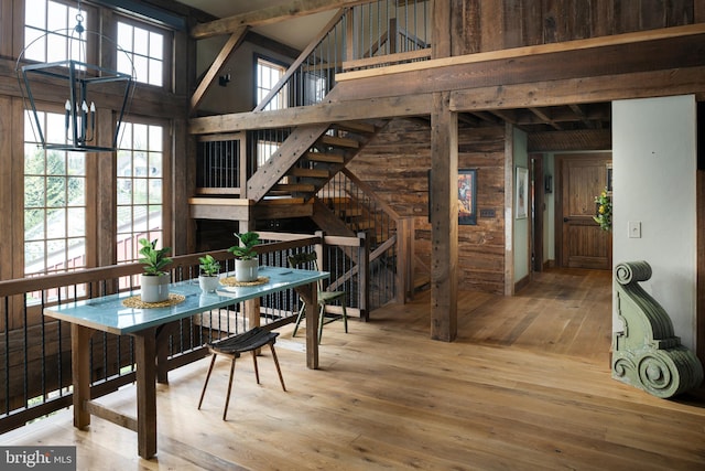 dining area with hardwood / wood-style floors, beam ceiling, high vaulted ceiling, and an inviting chandelier