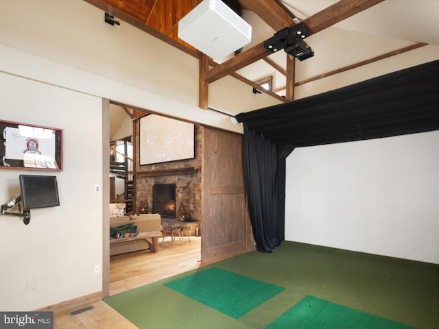 recreation room featuring hardwood / wood-style floors, golf simulator, beam ceiling, and a fireplace