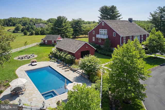 view of swimming pool featuring an outbuilding, a yard, a patio, and an in ground hot tub