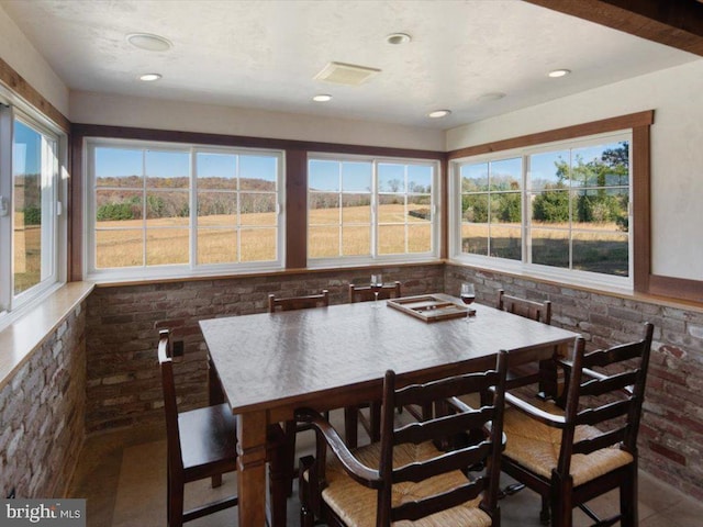 tiled dining room with brick wall and a healthy amount of sunlight