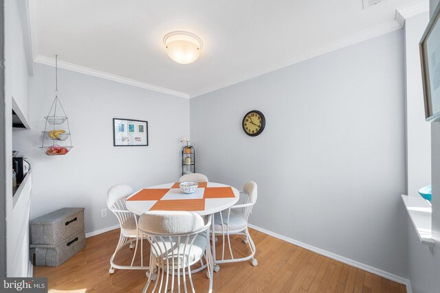 dining area featuring wood-type flooring and ornamental molding