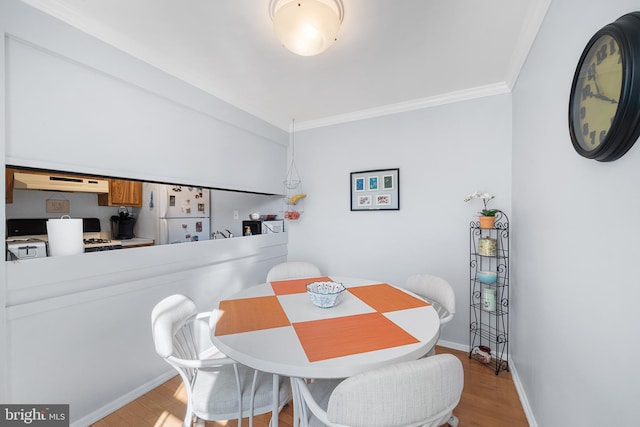 dining space with ornamental molding and light wood-type flooring