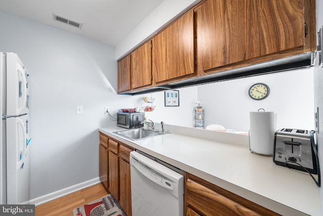 kitchen with sink, light wood-type flooring, and white appliances