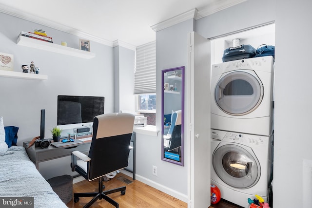 laundry area with ornamental molding, stacked washer / drying machine, and wood-type flooring