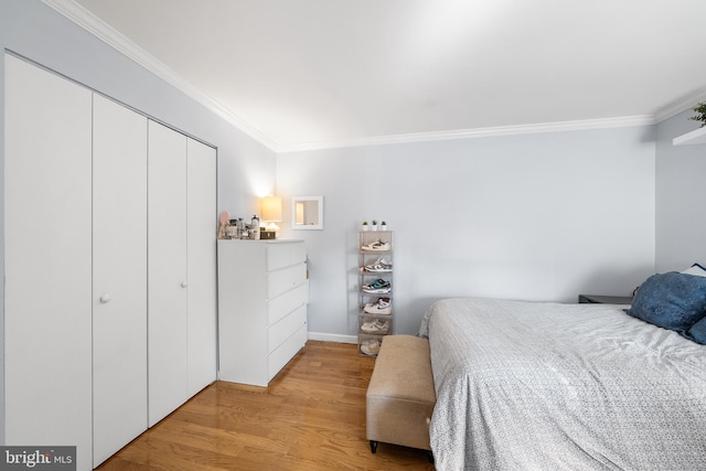 bedroom with light hardwood / wood-style floors, crown molding, and a closet