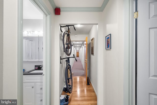 corridor featuring light hardwood / wood-style floors, crown molding, and sink