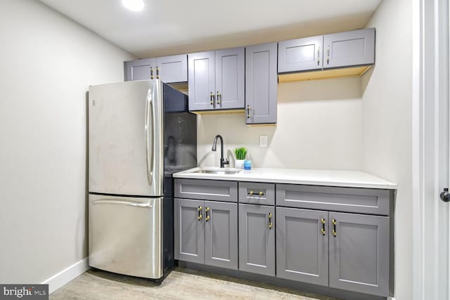 kitchen featuring gray cabinetry, sink, and stainless steel refrigerator