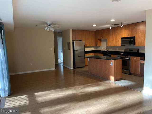 kitchen featuring sink, light hardwood / wood-style flooring, ceiling fan, appliances with stainless steel finishes, and a kitchen island