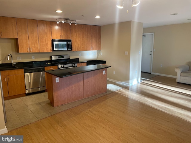 kitchen featuring sink, a center island, stainless steel appliances, a breakfast bar, and light wood-type flooring