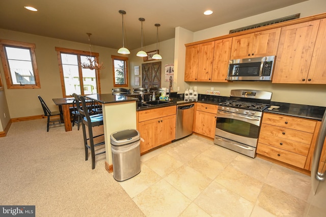 kitchen with kitchen peninsula, stainless steel appliances, a kitchen bar, pendant lighting, and an inviting chandelier