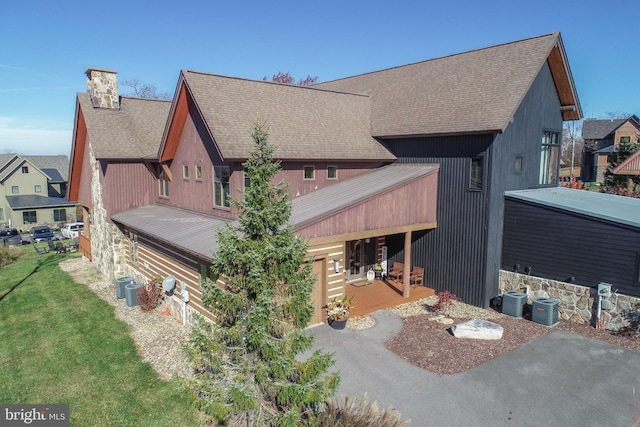 rear view of house with central air condition unit and a lawn