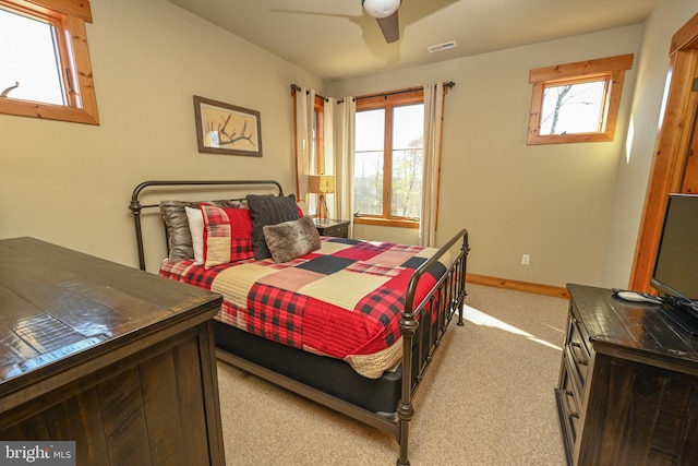 bedroom with multiple windows, light colored carpet, and ceiling fan