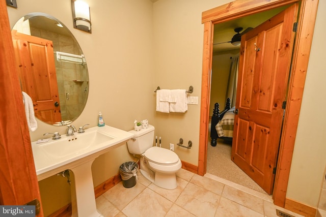 bathroom with toilet, walk in shower, sink, and tile patterned floors