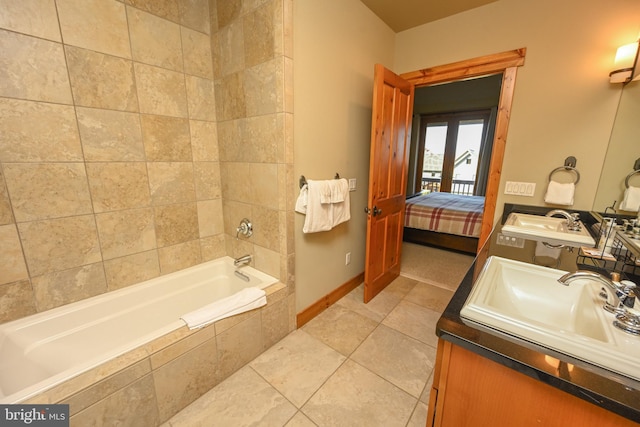 bathroom featuring vanity, a relaxing tiled tub, and tile patterned flooring