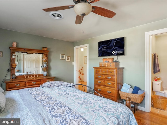 bedroom with ensuite bathroom, hardwood / wood-style floors, and ceiling fan